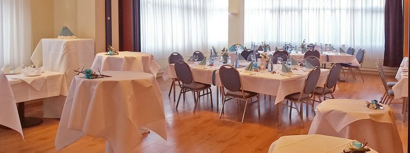 Eingedeckte Tische mit Bistrotischen im Vordergrund