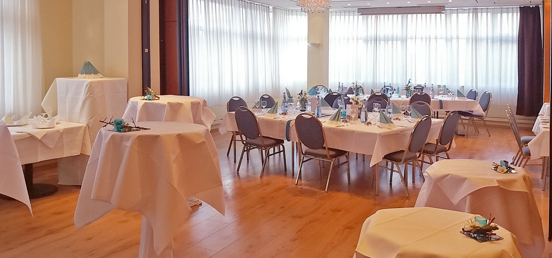 Eingedeckte Tische mit Bistrotischen im Vordergrund